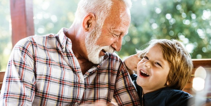 Grandfather enjoying time with his grandson while sitting around an outdoor dining area.